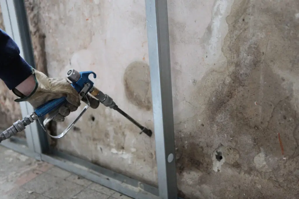 Man spraying inslation into walls